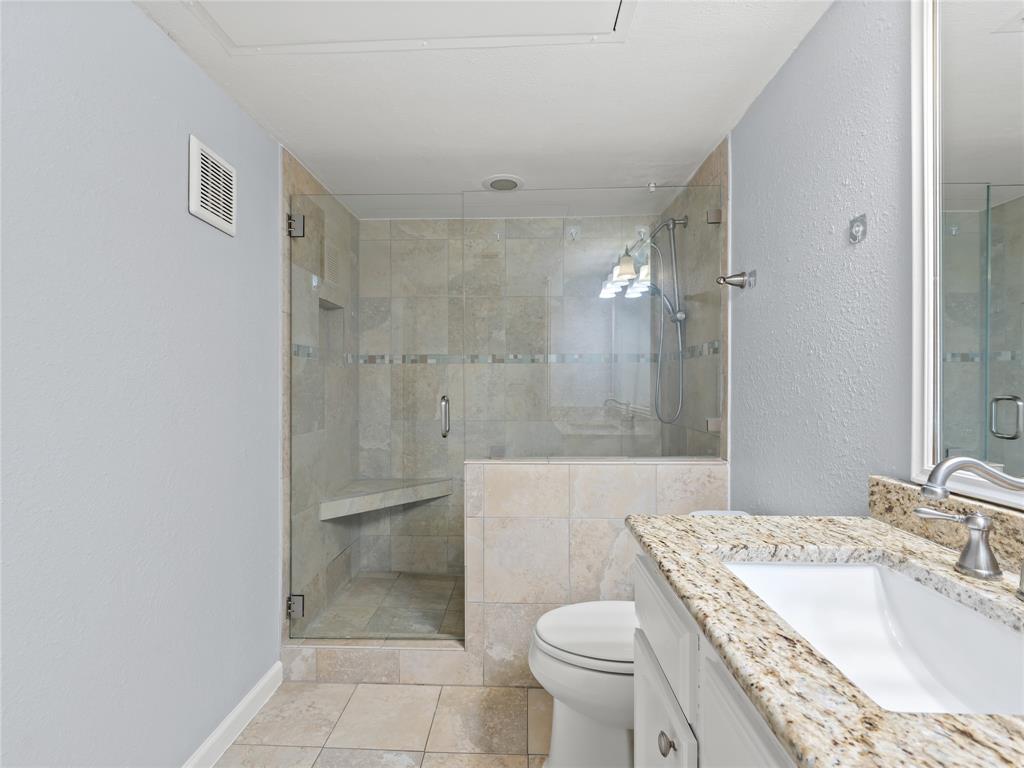 3101 Townbluff Drive, Unit 1024 Plano, TX 75075 - Photo 14 of 19 a bathroom with a granite countertop sink a toilet a mirror and shower