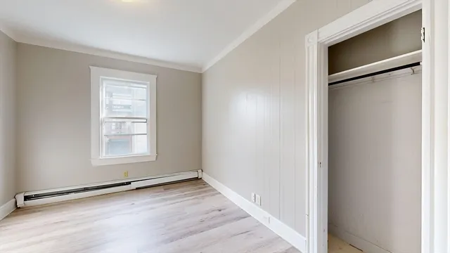 an empty room with wooden floor closet and windows