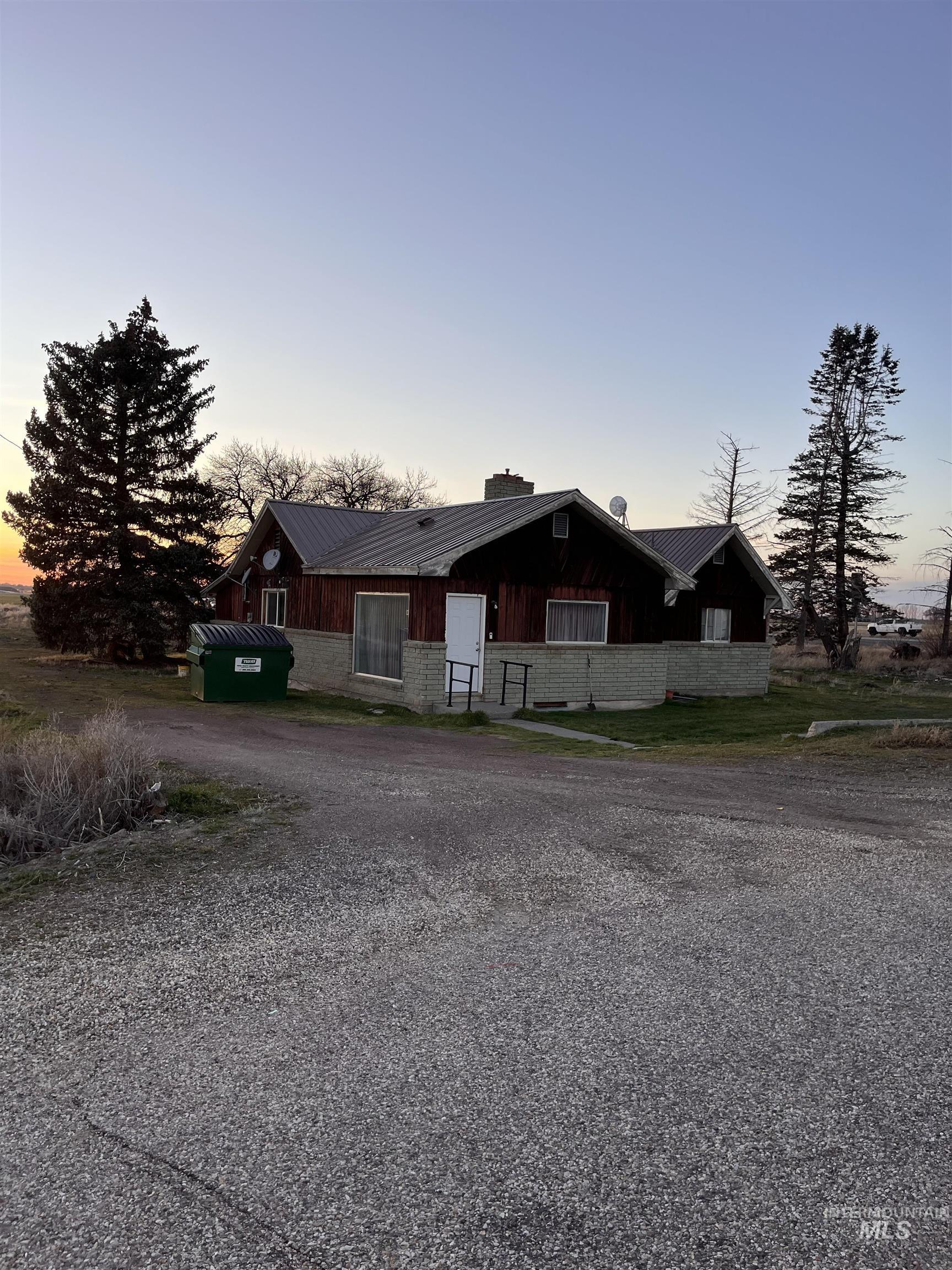 View of front of property featuring a chimney, a metal roof, driveway, and board and batten siding