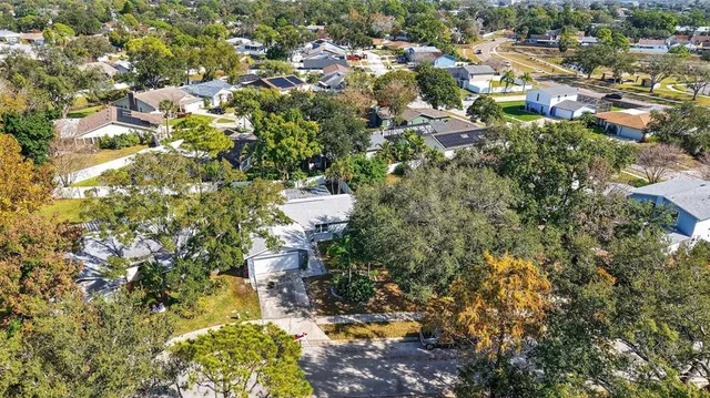 an aerial view of a houses with a yard and mountain view in back