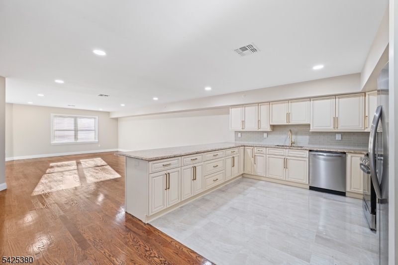 658 Market Street Paterson, NJ 07513 - Photo 18 of 19 a large white kitchen with stainless steel appliances granite countertop a stove a sink and white cabinets