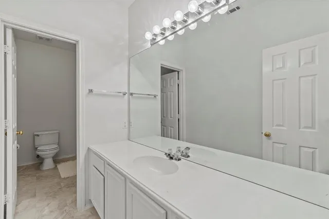 a bathroom with a granite countertop sink a toilet and a mirror