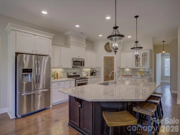 a kitchen with stainless steel appliances granite countertop a sink a stove a refrigerator cabinets and chairs