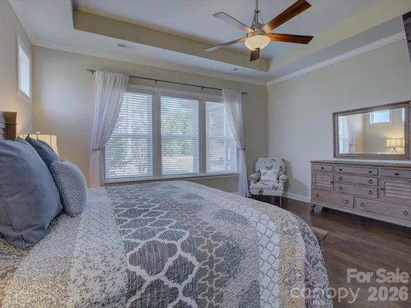 a spacious bedroom with a bed and a dresser with wooden floor