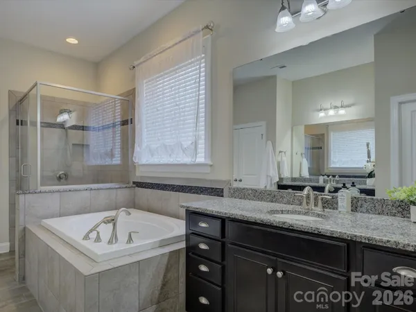 a bathroom with a granite countertop tub a sink and a window