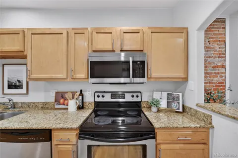 a kitchen with granite countertop a sink stove and microwave