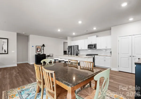 a kitchen with stainless steel appliances granite countertop a stove top oven a sink a dining table and chairs