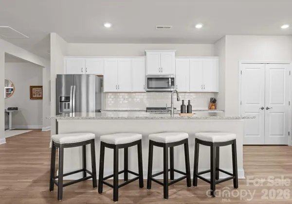 a kitchen with stainless steel appliances granite countertop a table chairs sink and cabinets