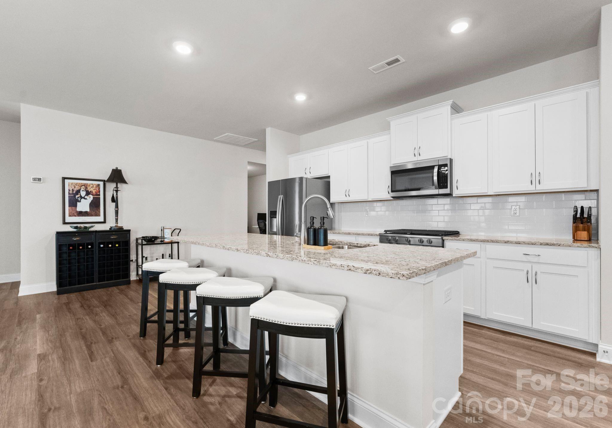 2004 Bonds Lane Fort Mill, SC 29715 - Photo 6 of 41 a kitchen with stainless steel appliances granite countertop a stove a sink a microwave a refrigerator a dining table and chairs with wooden floor