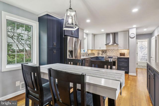 a living room with stainless steel appliances granite countertop furniture wooden floor and a kitchen view