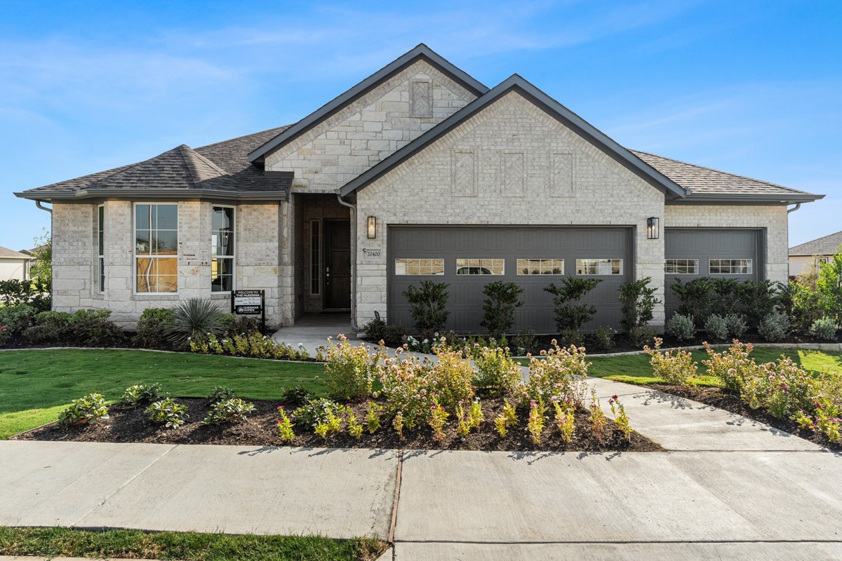 French provincial home with a front yard, brick siding, and stone siding