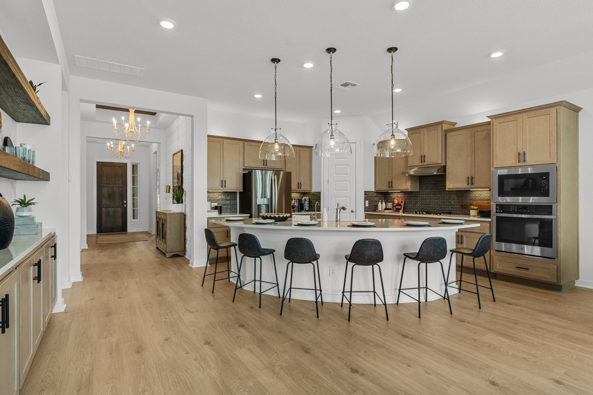 20400 Stelfox Street Manor, TX 78653 - Photo 9 of 37 Kitchen with a kitchen breakfast bar, appliances with stainless steel finishes, hanging light fixtures, a large island, and a chandelier