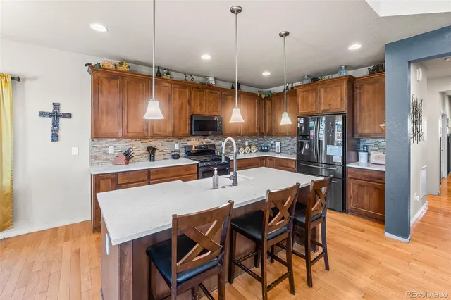 a kitchen with stainless steel appliances kitchen island granite countertop a table chairs and a refrigerator