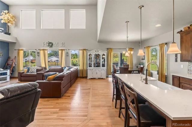 a large living room with stainless steel appliances kitchen island granite countertop a table chairs in it and a wooden floor