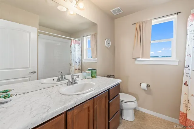a bathroom with a granite countertop sink a toilet and a mirror