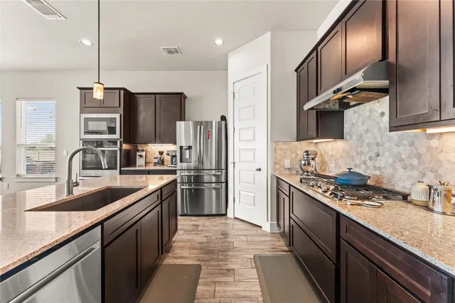 a kitchen with stainless steel appliances granite countertop a sink stove and refrigerator