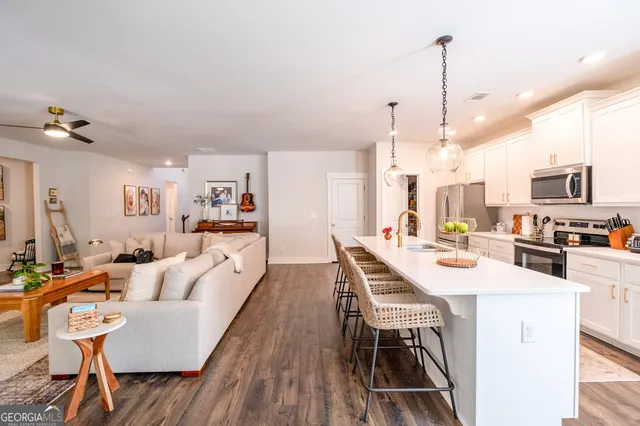 a kitchen with stainless steel appliances kitchen island granite countertop a refrigerator a stove a kitchen island a dining table and chairs