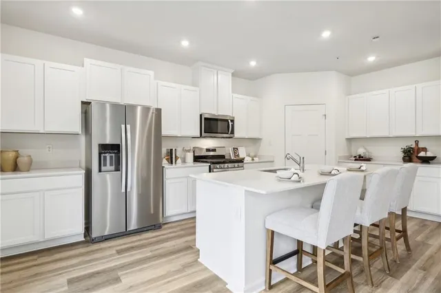 a kitchen with stainless steel appliances a refrigerator stove microwave and white cabinets