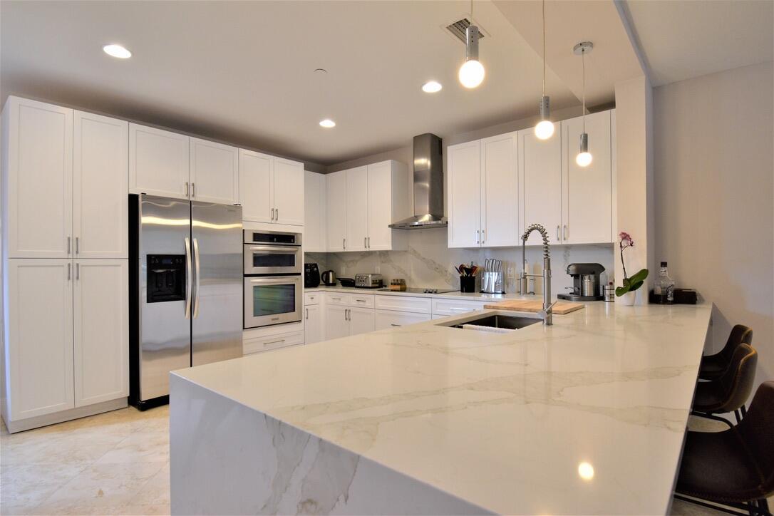 4866 Northwest 16th Avenue Boca Raton, FL 33431 - Photo 16 of 68 a large kitchen with kitchen island a large counter top space a sink stainless steel appliances and cabinets