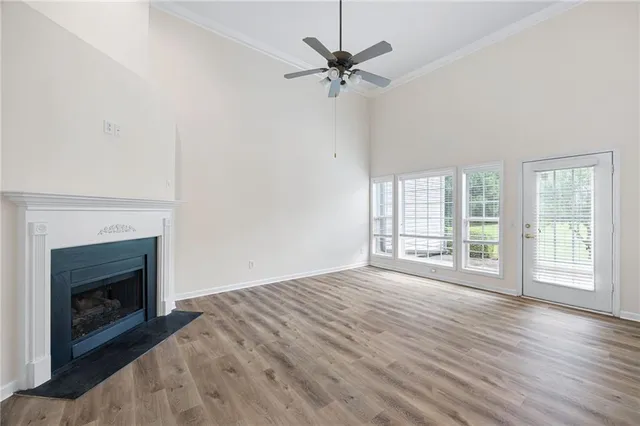 a view of an empty room with wooden floor fireplace and a window