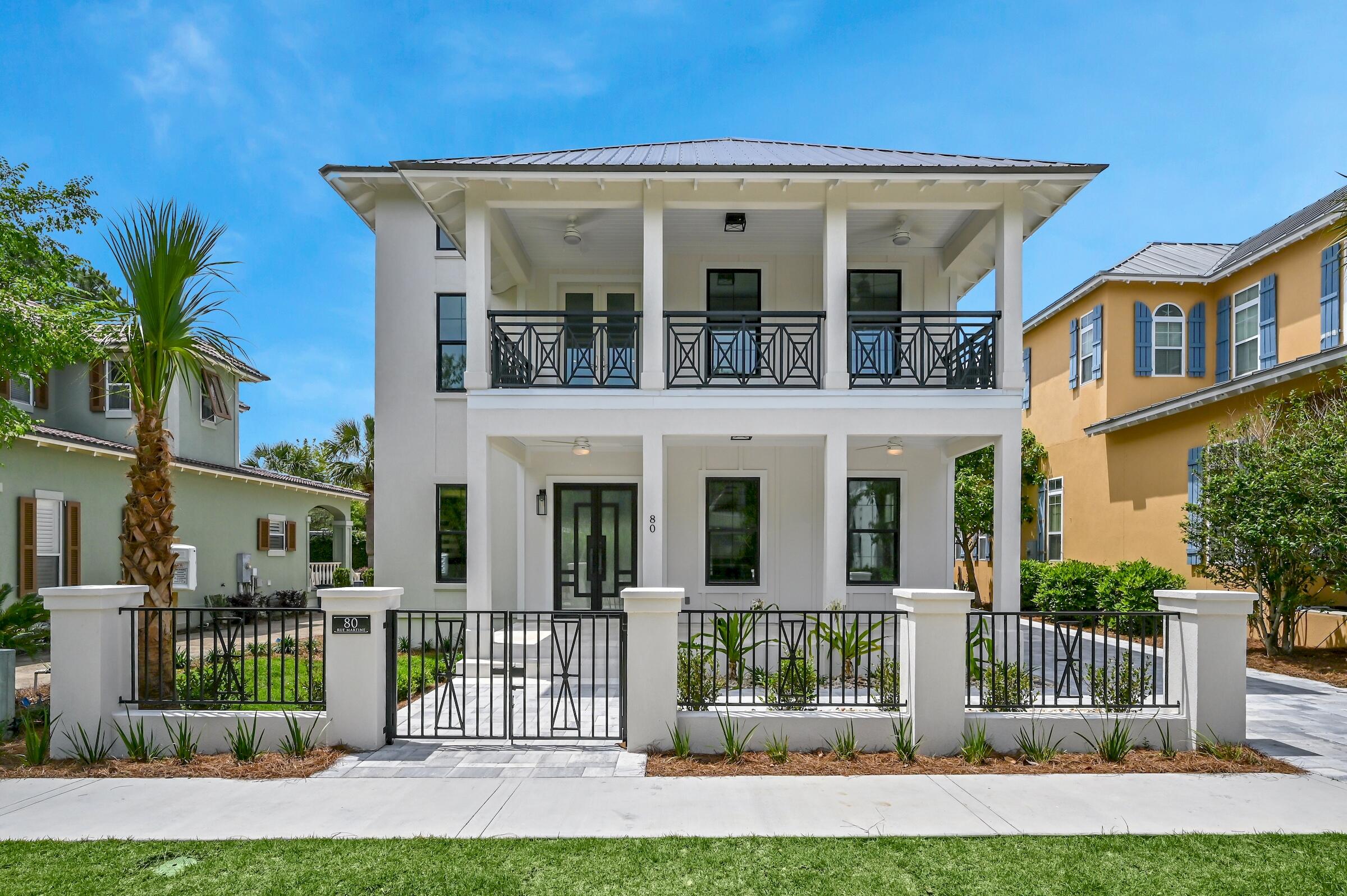a view of a white house with large windows and a yard