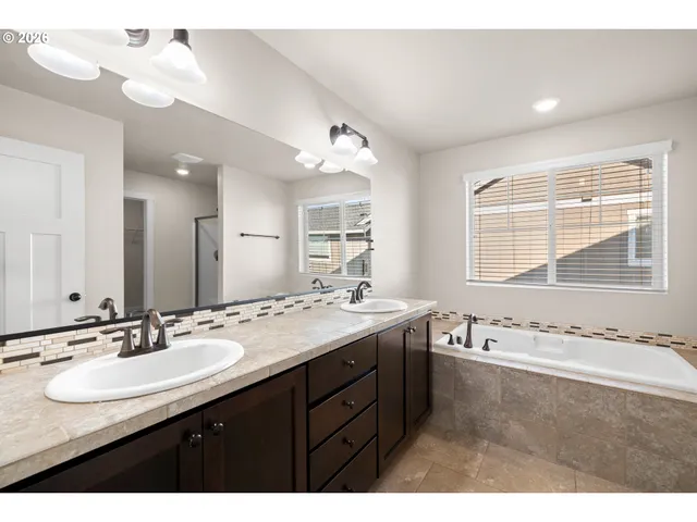 a bathroom with a sink double vanity granite tub and a mirror