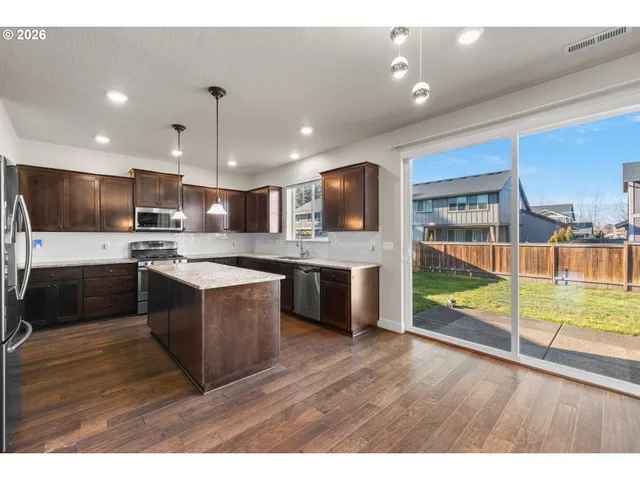 a kitchen with stainless steel appliances kitchen island granite countertop a stove a sink and a refrigerator