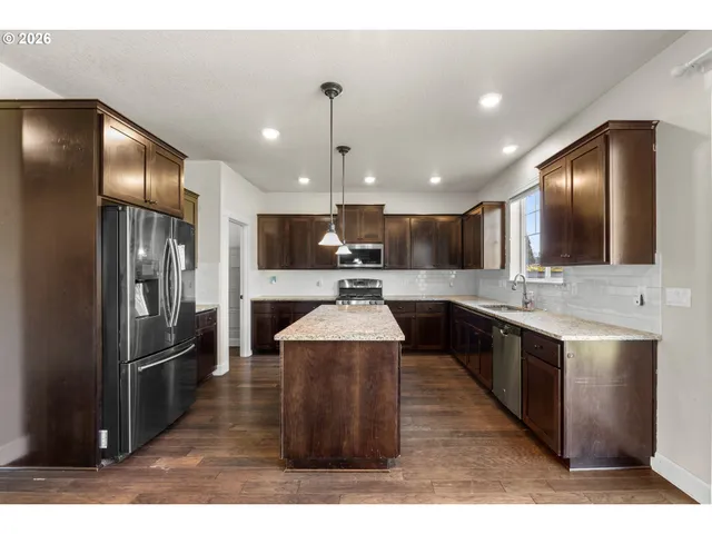 a large kitchen with stainless steel appliances kitchen island granite countertop a refrigerator and a stove