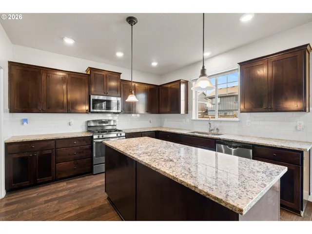 a kitchen with stainless steel appliances kitchen island granite countertop a sink and a stove