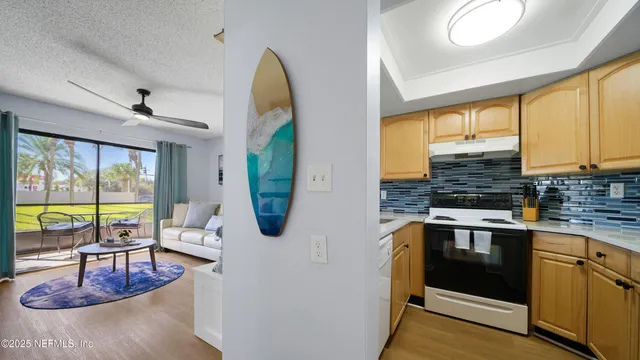 a kitchen with stainless steel appliances granite countertop a stove a sink and a granite counter tops with white cabinets next to a window