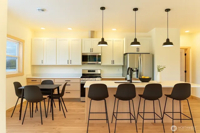 a view of kitchen with stainless steel appliances kitchen island granite countertop chairs and a wooden floor