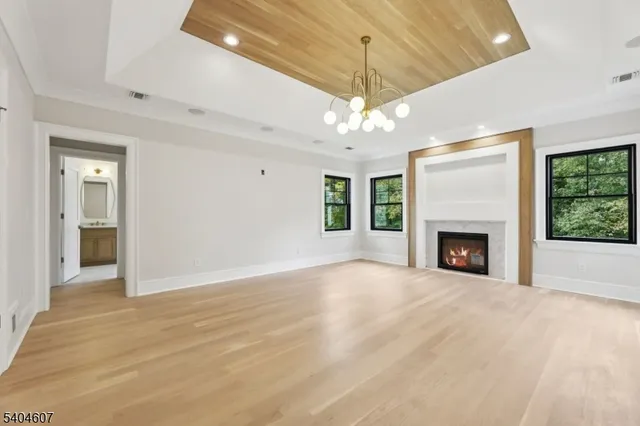 a view of an empty room with a fireplace a ceiling fan and windows