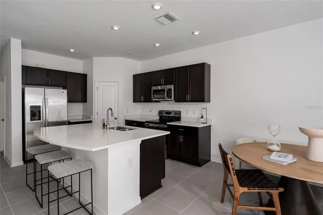 a kitchen with stainless steel appliances a sink a microwave a refrigerator and cabinets