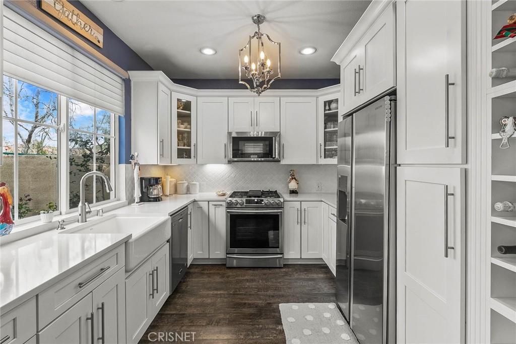 545 Lorabel Way, Unit D Simi Valley, CA 93065 - Photo 18 of 34 a kitchen with stainless steel appliances granite countertop a refrigerator a sink dishwasher a stove and a dining table with wooden floor