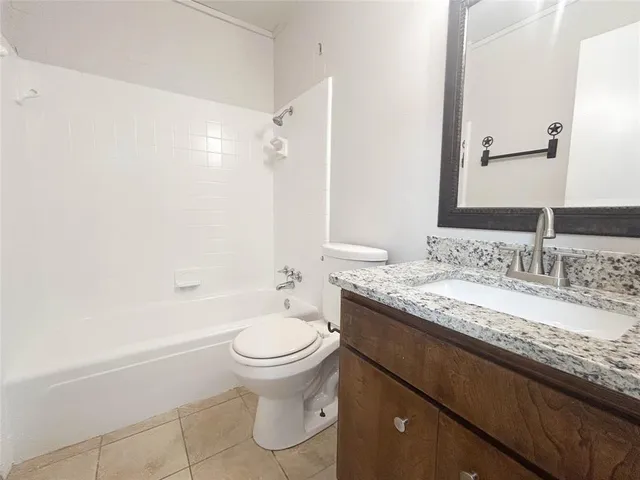 a bathroom with a granite countertop sink toilet mirror and a bathtub