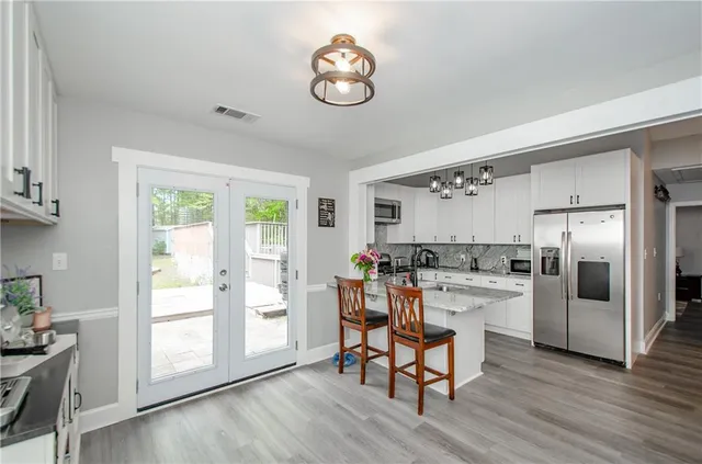 a kitchen with a refrigerator a stove a dining table and chairs with wooden floor