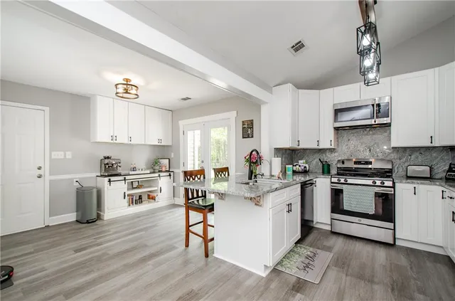 a kitchen with white cabinets stainless steel appliances and wooden floor