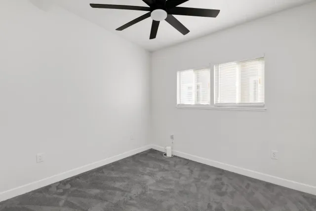 an empty room with a window and a fan