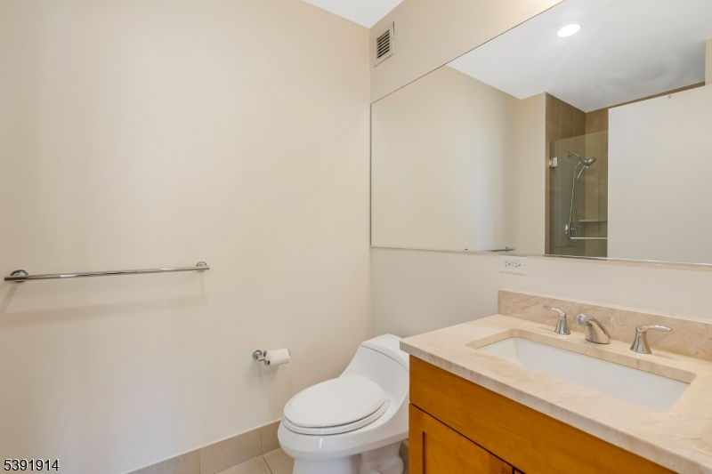 1 Spring Street, Unit 1704 New Brunswick, NJ 08901 - Photo 25 of 44 a bathroom with a granite countertop sink toilet and a mirror