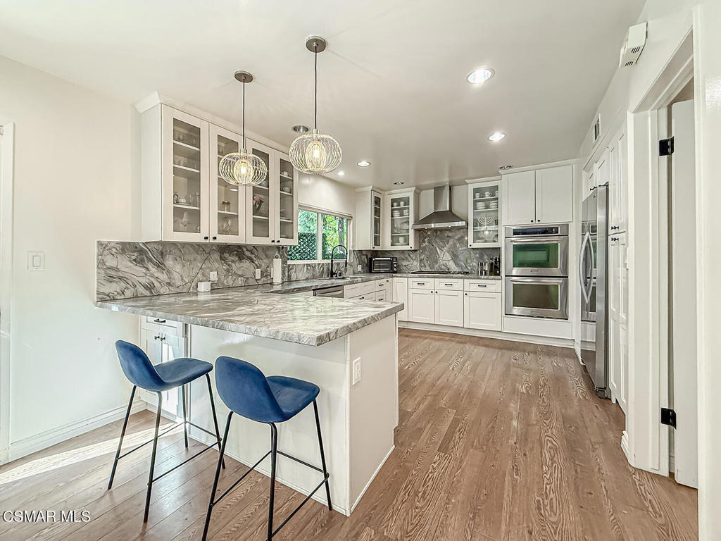 4184 Lanai Road Encino, CA 91436 - Photo 8 of 32 a kitchen with kitchen island granite countertop wooden floor and a refrigerator