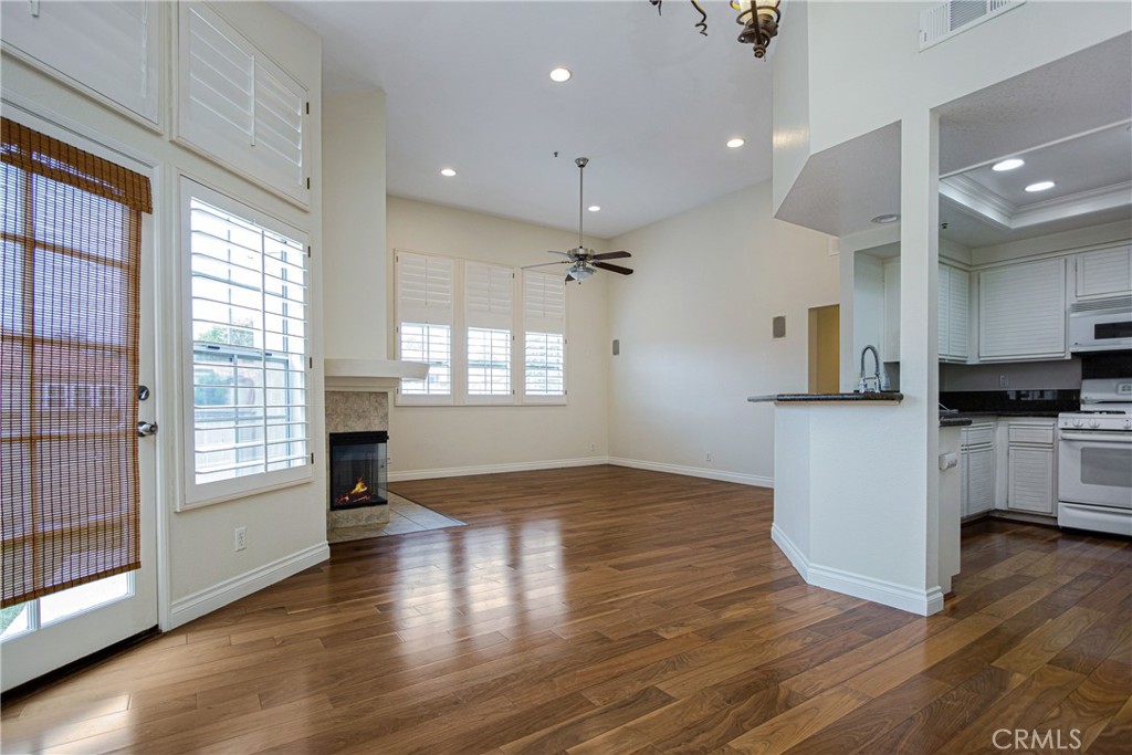 23 Ericson Aisle Irvine, CA 92620 - Photo 3 of 28 an empty room with wooden floor kitchen view and windows