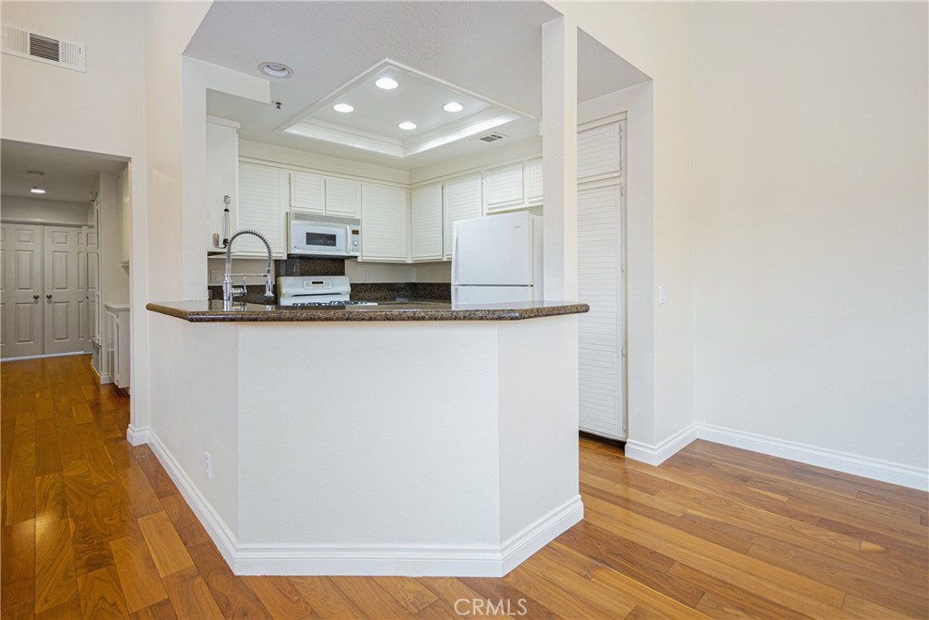 23 Ericson Aisle Irvine, CA 92620 - Photo 8 of 28 a kitchen with stainless steel appliances granite countertop a sink a stove a refrigerator a sink and dishwasher with wooden floor