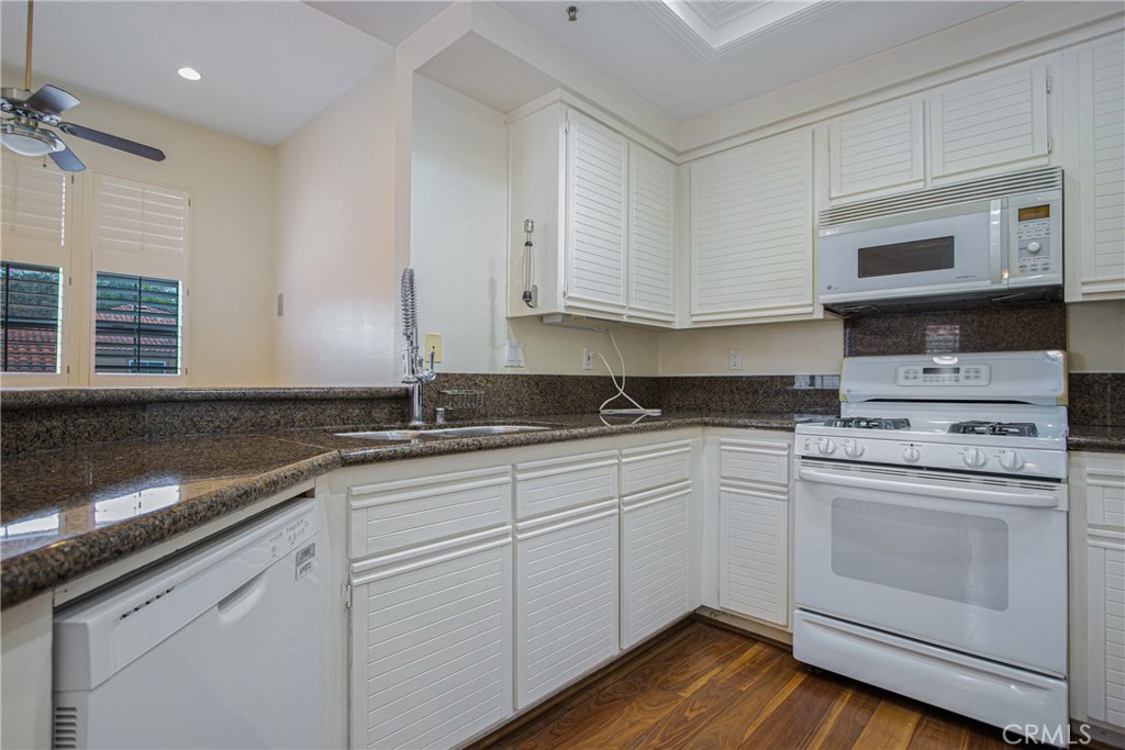 23 Ericson Aisle Irvine, CA 92620 - Photo 9 of 28 a kitchen with granite countertop white cabinets and white appliances