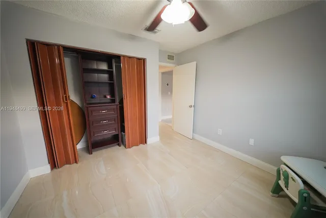 a bedroom with a bed and a flat tv screen on dresser