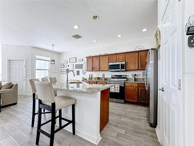 a kitchen with stainless steel appliances granite countertop a refrigerator a stove top oven a sink dishwasher and white cabinets with wooden floor