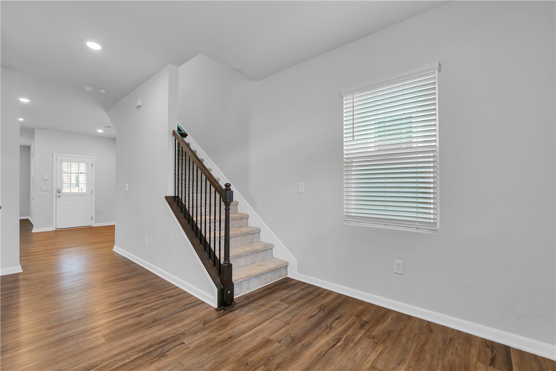 8 Leander Drive Greer, SC 29651 - Photo 13 of 31 A welcoming entryway boasts warm hardwood flooring, leading to a carpeted staircase with dark railings and a naturally illuminated window.