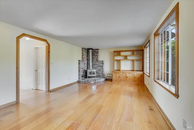 a view of an empty room with a window and wooden floor