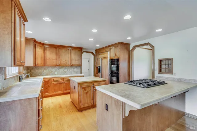 a kitchen with stainless steel appliances granite countertop a sink dishwasher stove top oven and refrigerator with wooden floor