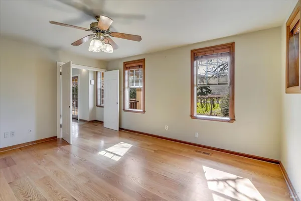 a view of empty room with wooden floor and fan