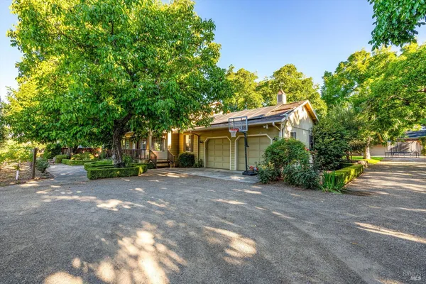 a view of a house with large trees and a yard